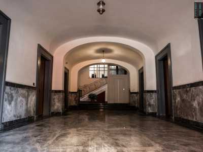 L�atrio di accesso � contraddistinto da pannelli di marmo grigio e nero sul pavimento e su parte delle mura laterali, quest�ultime scandite da una serie di porte in legno. Sul bianco soffitto a volta pendono due lanterne dorate che ci fanno luce fino al vano scala